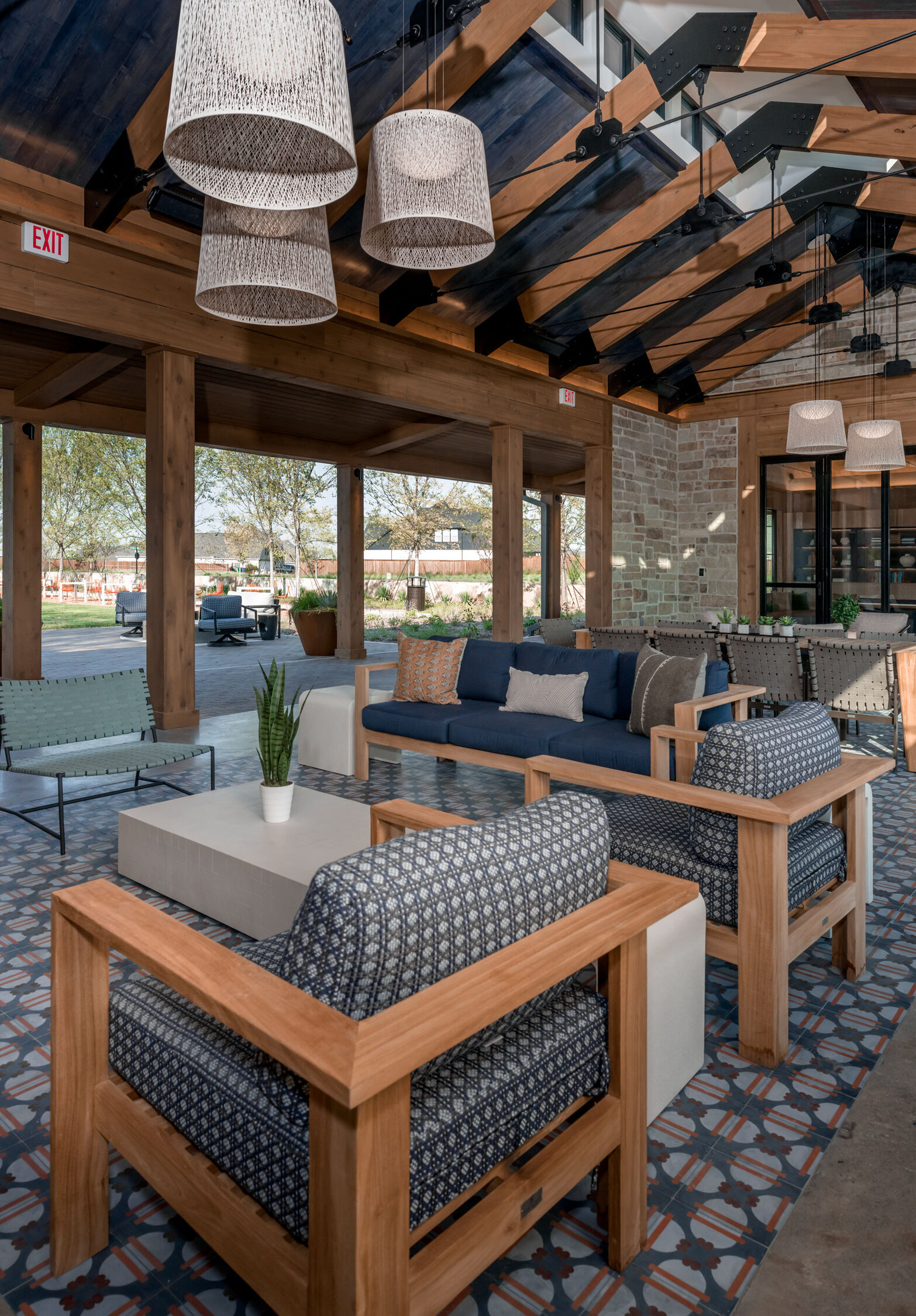 Open-air clubhouse lounge with wooden beams, patterned tile flooring, and modern seating at Hillstead.