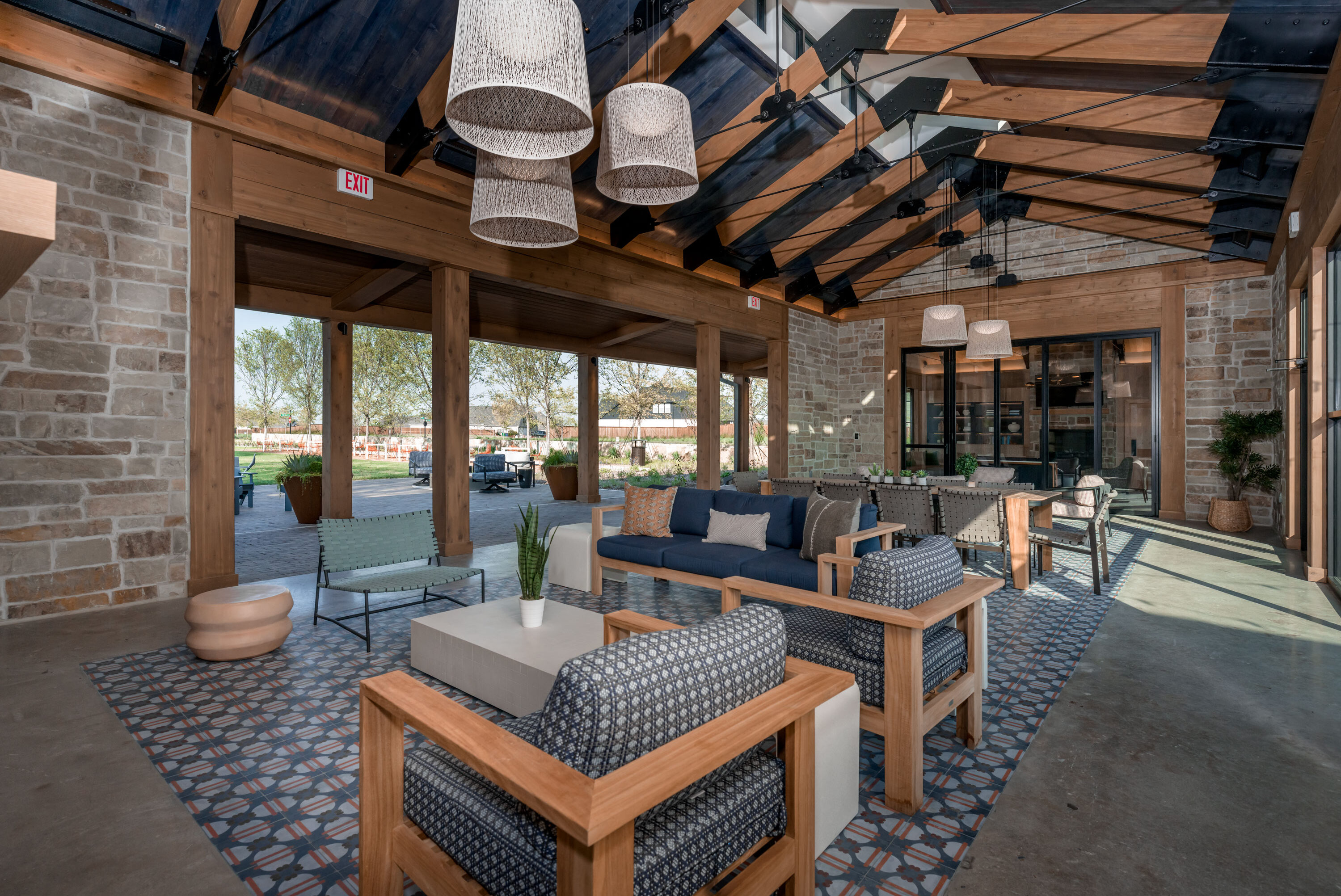 Open-air clubhouse lounge with wooden beams, patterned tile flooring, and modern seating at Hillstead.