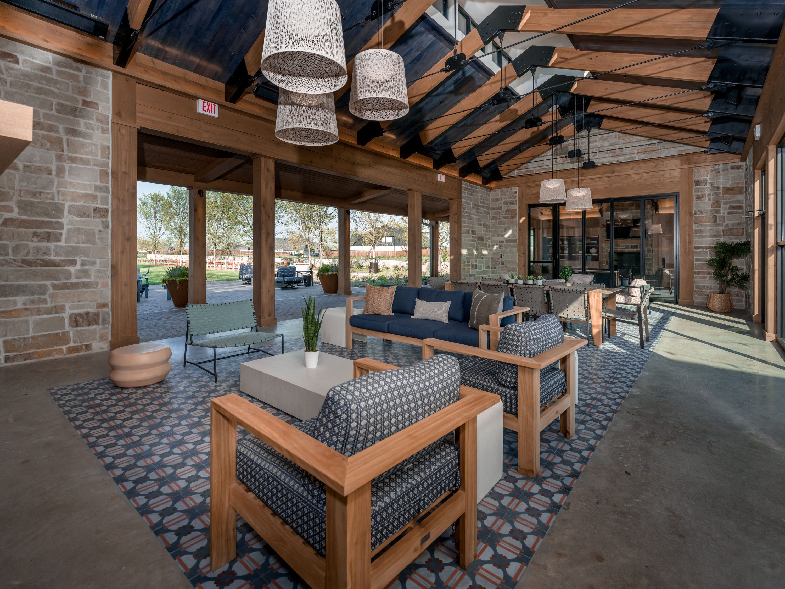 Open-air clubhouse lounge with wooden beams, patterned tile flooring, and modern seating at Hillstead.